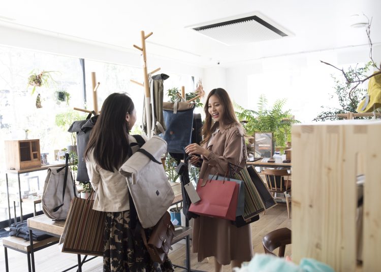 Two female college students shopping at clothes shops in cities.